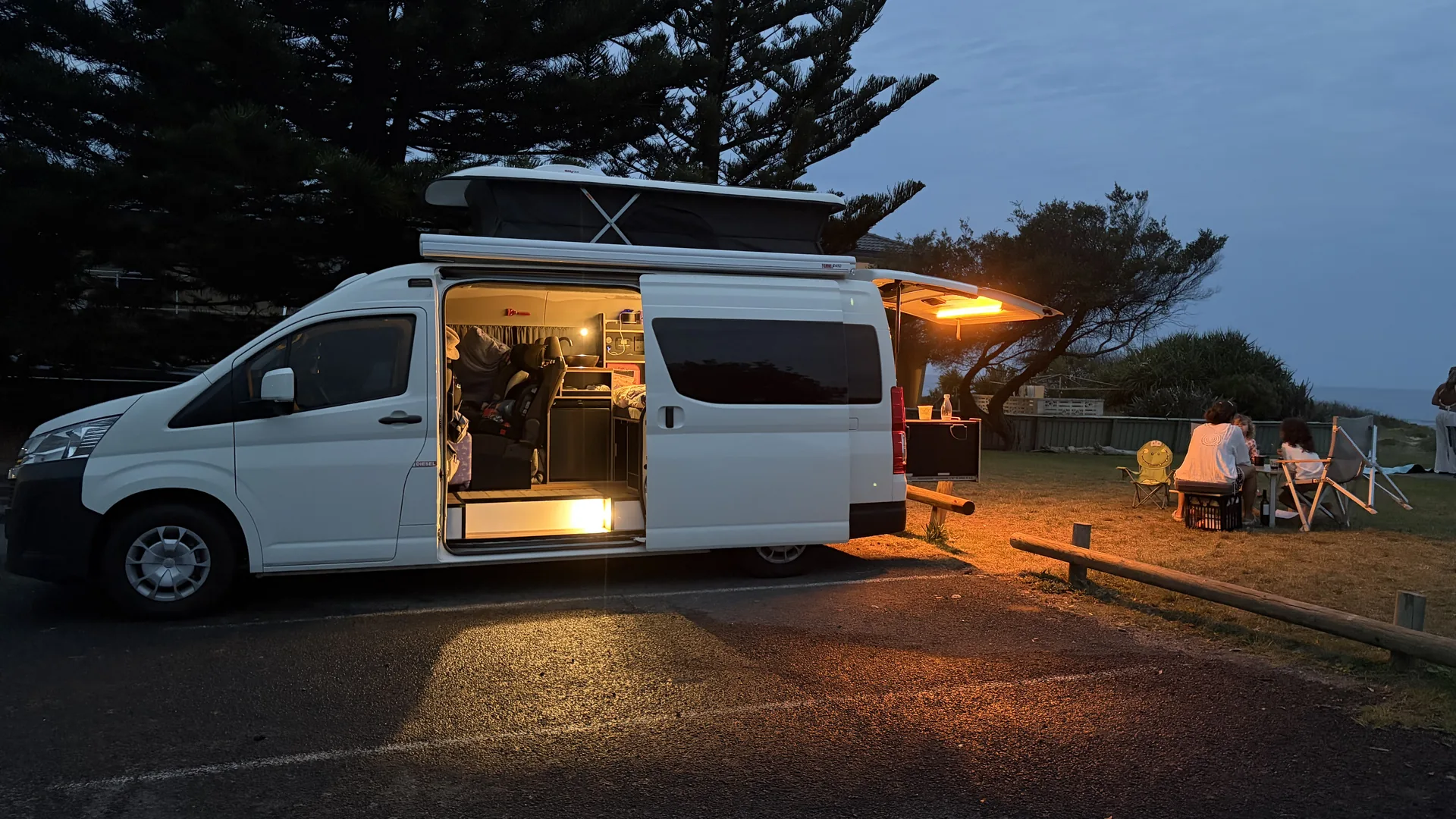Toyota Hiace H300 full conversion with pop-top at a coastal campsite