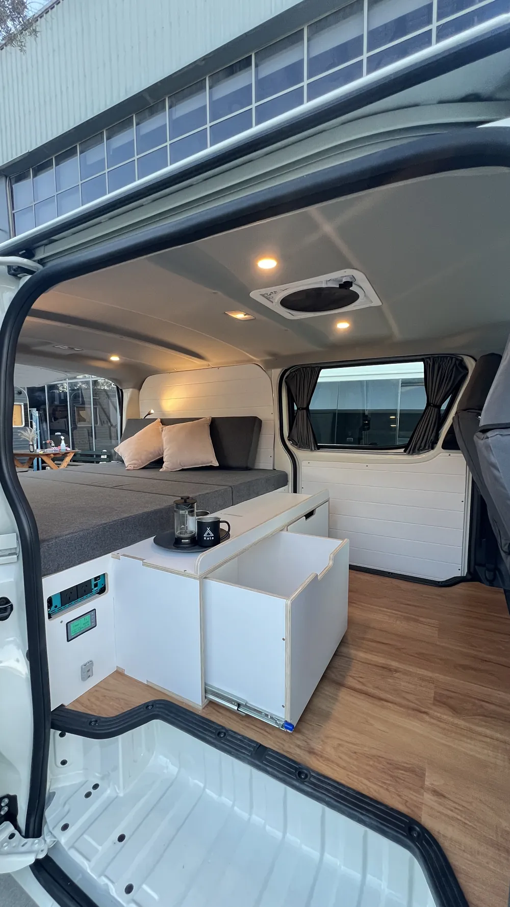 Interior of a fully converted Toyota Hiace H300 — bed and kitchen