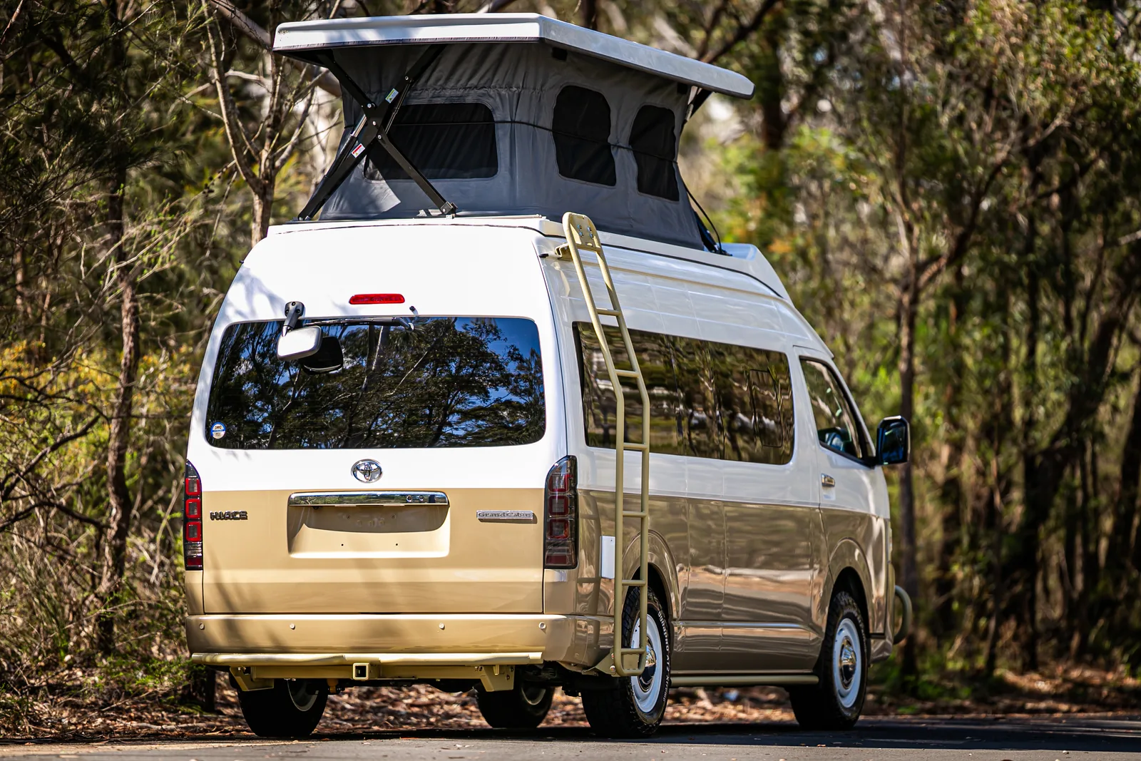 Rear view of a HiAce with the pop-top raised and a roof ladder