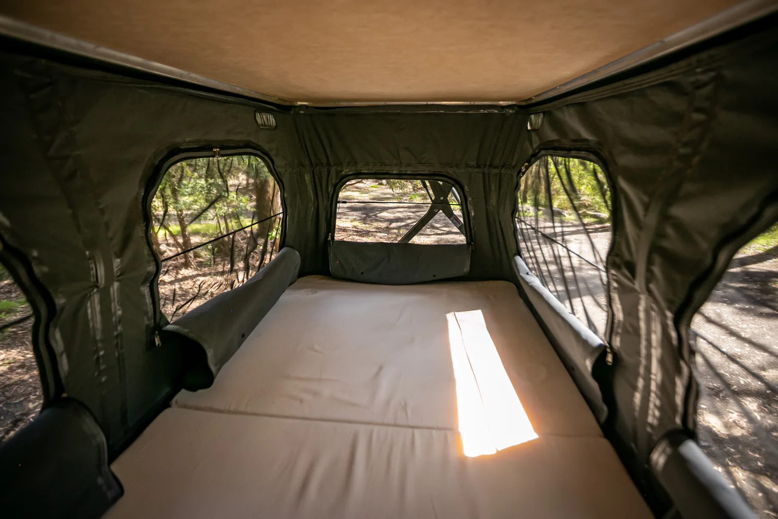 Inside the raised pop-top — double bed with canvas windows on three sides
