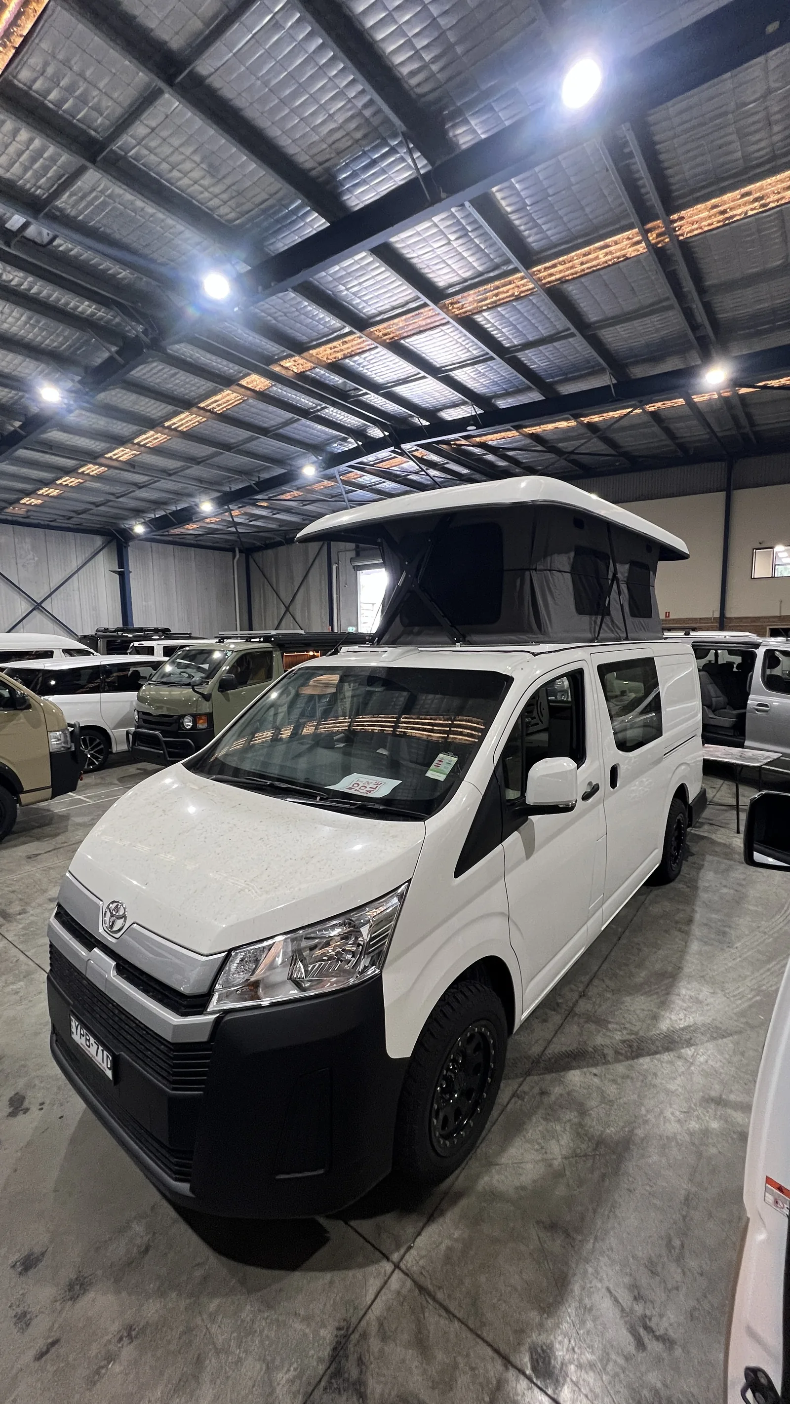 White HiAce with pop-top raised inside the workshop